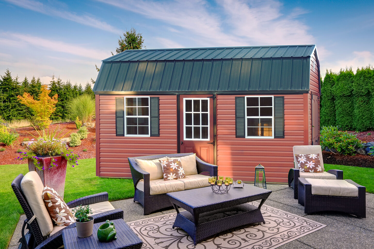 red and green trimmed shed with curved green metal roof and patio furniture in front